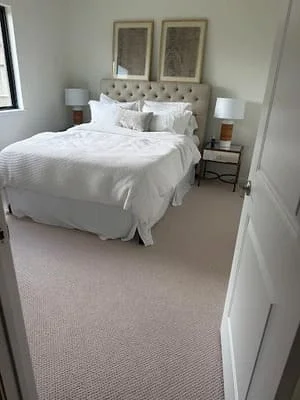 Master bedroom with new carpet, painted walls, tufted headboard, and updated fixtures