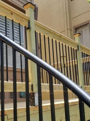 Black metal stair railing with steel handrail and vertical balusters against cream wall