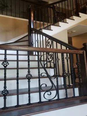 Wrought iron stair railing with decorative scrollwork and geometric metalwork on interior staircase