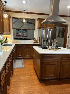 Kitchen with dark wood cabinets, white quartz counters, island, stainless appliances, and hardwood floors